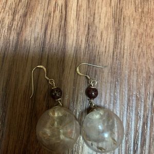 Unique white dandelion pressed in a glass ball with a red ruby stone